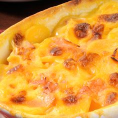 a casserole dish with cheese and meat in it on a red table cloth