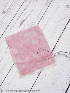 a piece of pink fabric with a heart on it sitting on top of a white wooden floor