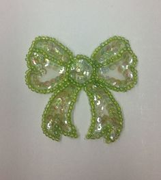 a green bow brooch with sequins on it