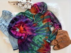 a tie - dyed hoodie, jeans and handbag are laid out on a white furnishing