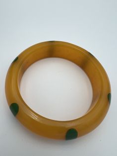 Vintage Howard Kronimus signed injected light butterscotch  Bakelite with green 6 dot bangle bracelet Bangle is signed HK and in overall very good condition  Bangle is 3/4" thick  2.5" internal diameter  2024 Lawson Retro Green Bangle Bracelets, Retro Green Bracelet For Gift, Retro Green Bracelet Gift, Retro Green Bracelets For Gifts, Retro Green Bracelets For Gift, Green Retro Bracelet As A Gift, Vintage Adjustable Green Bangle, Vintage Green Adjustable Bangle, Adjustable Green Vintage Bangle