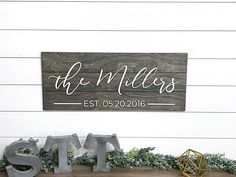 a wooden sign that says the miles and sits on top of a shelf with greenery