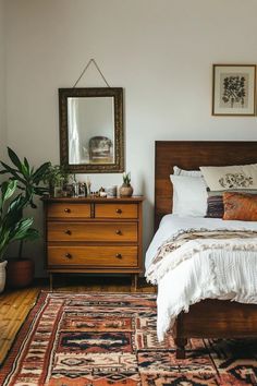 a bedroom with a bed, dresser and mirror on the wall next to a potted plant