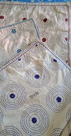 two white and blue bedspreads on top of each other with circles in the middle