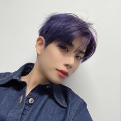 a woman with short purple hair wearing a denim shirt