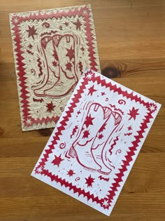 two red and white cards with cowboy boots on them sitting on a wooden table next to each other