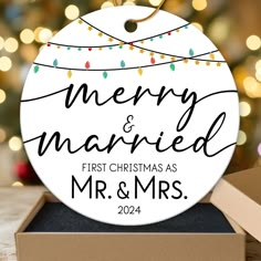 a merry and married ornament in a box with christmas lights on the background