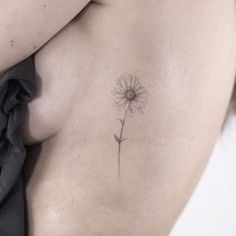 a woman's stomach with a small flower tattoo on her left side ribcage