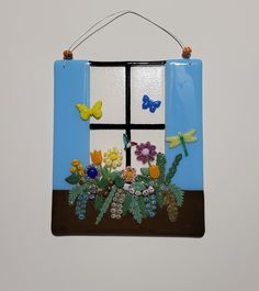 a window decorated with flowers and butterflies on a wall hanging from a hook in the shape of a flower box