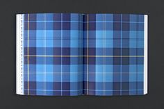 an open book with blue and yellow plaid on the cover, sitting on a black surface