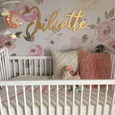 a white crib with pink and gold decor on the wall next to a bed