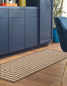 a rug is on the floor in front of a blue cabinet and chair with a plant next to it