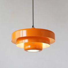 an orange pendant light hanging from a ceiling