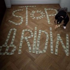 a dog is standing on the floor in front of a sign made out of money