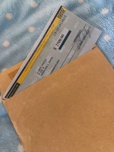 a brown envelope with a ticket inside on a blue and white polka doted blanket