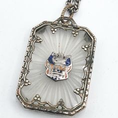 an antique silver and glass pendant with a cat on it's face in the center