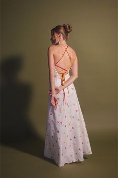 The designer Estefanía Álvarez's mastery in balancing modern shapes with romantic femininity is evident in the Rainbow Cherry Tomato dress. Crafted with lightweight and lustrous linen, this elegant and cheerful dress is detailed with an embroidery of flowers and cherry tomatoes, adorned with a delicate multicolored bias ribbon that enhances the back. Pair it with a simple pair of low-heeled sandals and an open back for a bold yet sophisticated look. Summer Dress With Floral Embroidery And Fitted Bodice, Fitted Bodice Floral Embroidery Summer Dress, Fitted Linen Embroidered Summer Dress, Fitted Linen Embroidered Dress For Summer, Fitted Embroidered Linen Dress For Summer, Fitted Linen Dress With Floral Embroidery For Summer, Fitted Linen Dress With Floral Embroidery For Spring, Elegant Summer Linen Dress With Floral Embroidery, Fitted Linen Dress With Floral Embroidery