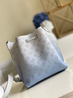 The Muria bucket bag is made from Mahina calf leather with a gradient color treatment from pastel to neutral. Combined with the calf leather’s perforated Monogram motif, the effect is dazzling. The Muria can be carried by hand with the braided top handle or with its long leather strap. Detailed Features 25 x 25 x 20 cm (Length x height x width ) Gradient Blue Mahina perforated calf leather Calf-leather trim Microfiber lining Silver-color hardware 2 compartments with a separative locked zipped pocket Leather drawstring to secure belongings Name tag Key bell 4 protective metal bottom studs Strap: Removable, adjustable Strap Drop: 45.0 cm Strap Drop Max.: 55.0 cm Handle: Single Vuitton Bag, Gradient Color, Leather Trims, Bag Sale, Silver Color, Calf Leather, Top Handle, Bucket Bag, Fashion Bags