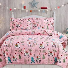 a pink christmas themed comforter set on a bed