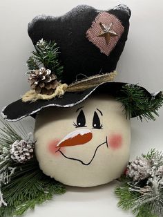 a snowman with a black hat and pine cones