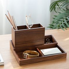 a wooden desk organizer with glasses, pen holder and notepad in it on a table next to a laptop