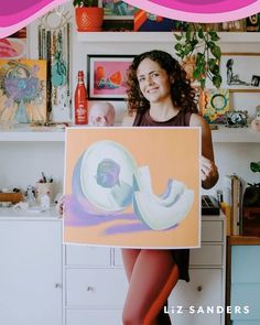 a woman holding up a painting in front of her face