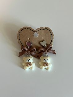 ୨୧  ⋅ For my bear lovers, this is the perfect earrings for you!   ୨୧  ⋅ Materials: - Heart stud with backing - Bear charm  - brown ribbon  - Silver plated looping Brown Earrings Aesthetic, Cute Bear Keychain, Aesthetic Stud Earrings, Bear Earing, Cute Earing, Jewellery Lookbook, Coquette Cottage Core, Kawaii Coquette, Teddy Bear Earrings