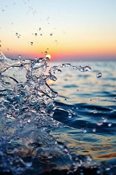 water splashing on top of the ocean with sunset in the background and blue sky