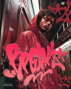 a man in a red hoodie standing next to a subway car with graffiti on it