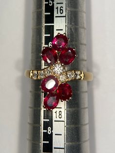 a close up of a ring on top of a measuring ruler with red and white stones