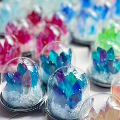 many different colored crystals in glass bowls on top of a table with white and blue marbles