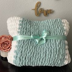 a blue and white crocheted blanket with a bow on it