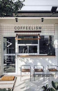 the outside of a coffee shop with chairs and plants