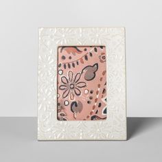 a white frame with a pink and black flower design on it, sitting on a table