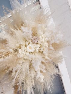 an arrangement of white flowers and feathers in front of a door