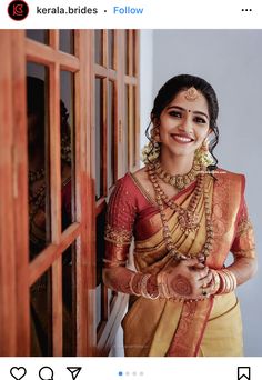 a woman in a yellow and red sari standing next to a window with her hands on her hips