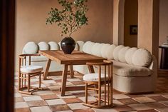 a table with chairs and a vase on it in front of a white sectional couch