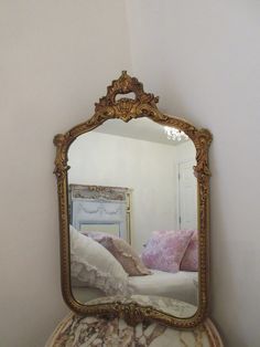 a mirror that is sitting on top of a dresser next to a bed and pillows