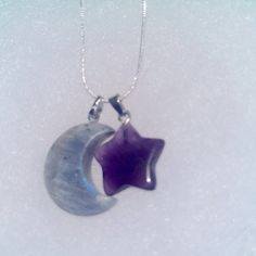 a necklace with a purple star hanging from it's side on a white surface