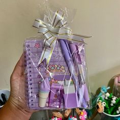 a person holding up a purple notebook and pen in front of some cupcakes