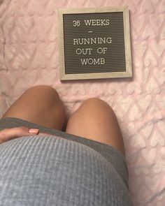 a woman laying on top of a bed next to a sign that reads, 35 weeks running out of womb