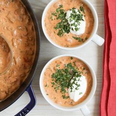 two bowls of soup with sour cream and parsley on top, next to a red napkin