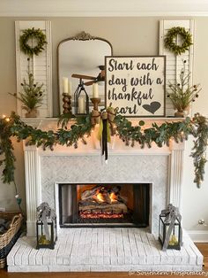 a fireplace decorated for christmas with greenery and candles on the mantel above it is a sign that says start each day with a happy thanksgiving heart