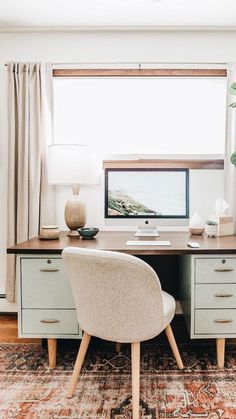 a desk with two chairs and a computer on it in front of a large window