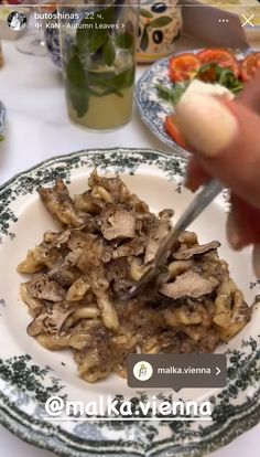 a person cutting food on top of a white and blue plate with green trimmings