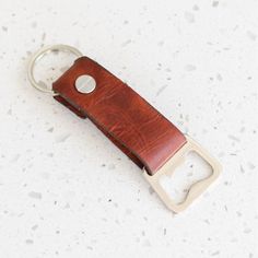 a brown leather keychain with a metal clip on it's side and a hole in the middle