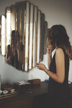 a woman standing in front of a mirror looking at her cell phone