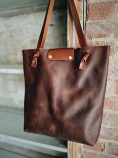 Looking for something deep and rustic? Here’s your dream bag for all day, every day. With a large interior pocket and adjustable knotted straps you’re good to go. Optional snap closure. 15” w by 14” h by 4” Rustic Bags With Leather Handles For Everyday, Everyday Brown Shoulder Bag With Brass Hardware, Everyday Shoulder Bag With Snap Closure And Double Handle, Double Handle Shoulder Bag With Snap Closure, Rustic Everyday Bags With Leather Lining, Rustic Bags With Leather Lining For Everyday Use, Rustic Bags With Leather Handles For Daily Use, Rustic Shoulder Bag With Leather Handles For Travel, Rustic Tote Bag For Everyday Use