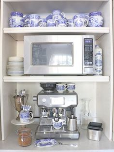 a coffee maker is on top of a shelf with blue and white dishes in front of it