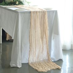 the table is set with white linens and long strands of yarn hanging from it